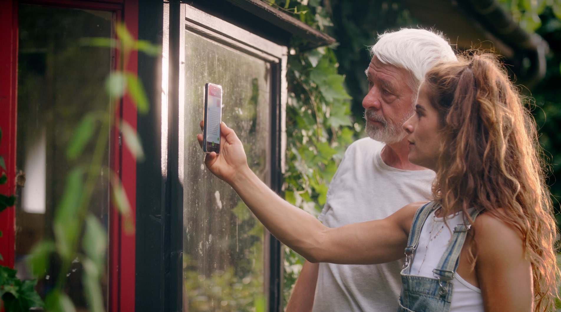 Twee mensen bekijken samen een reparatie aan een kozijn op een telefoon